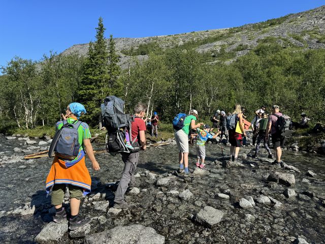 Дети с рюкзаками идут по каменистому берегу в горах